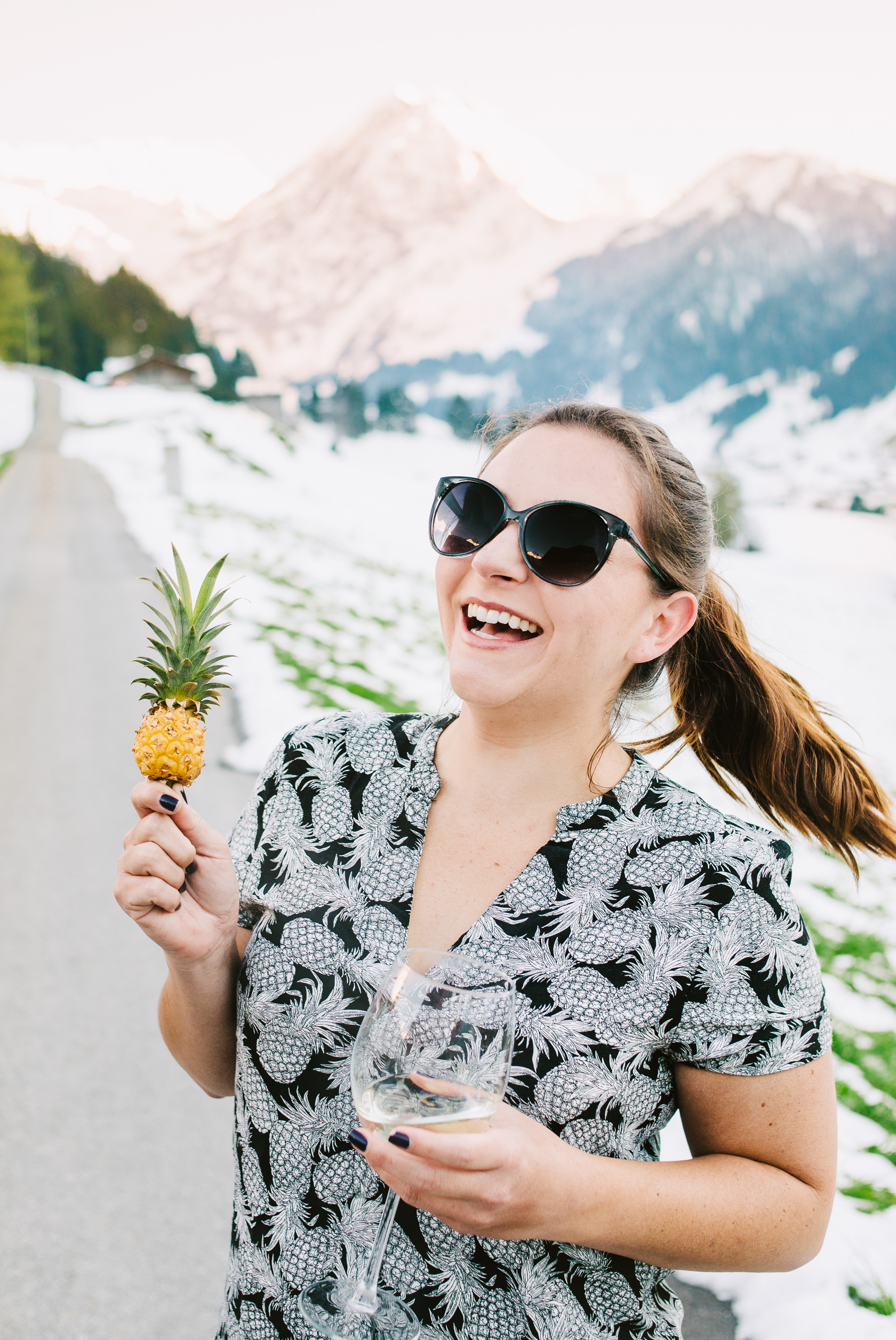 laughing woman with miniature pineapple and a glass of wine in t