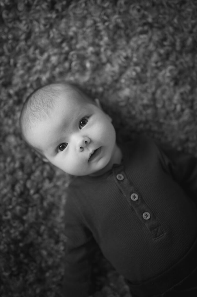 Bebis fotograferad liggande på en fårskinnsfäll