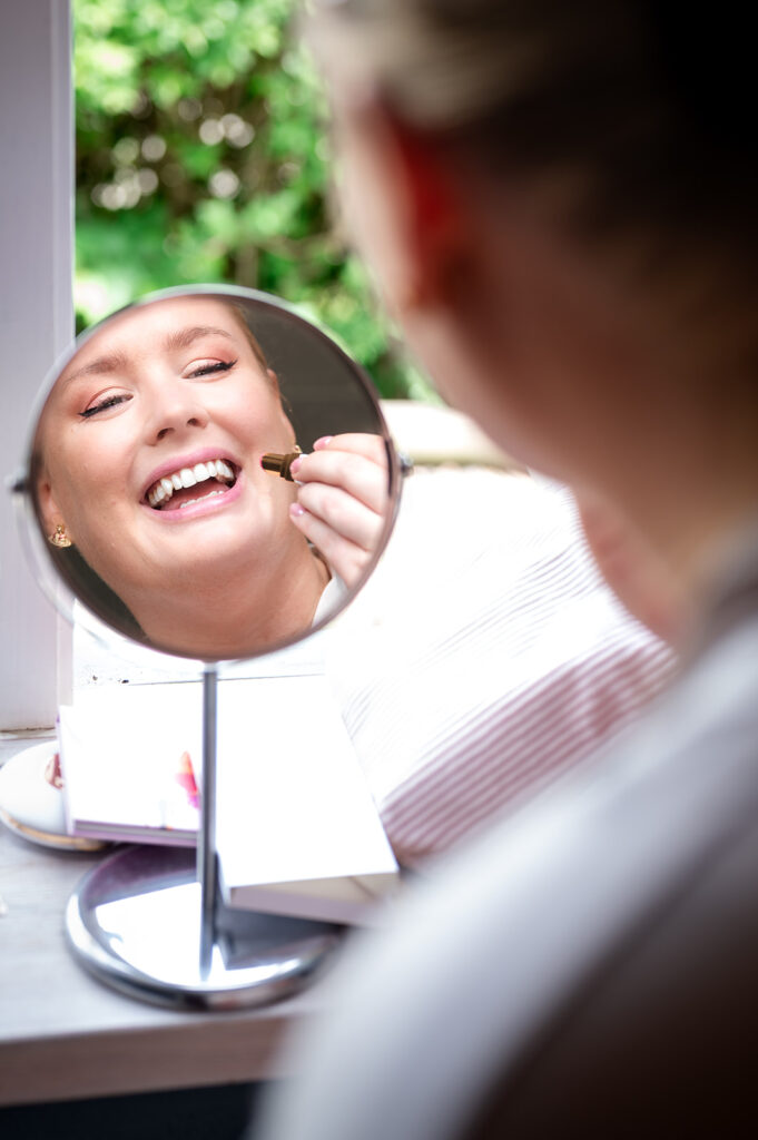 Glad brud sminkar sig och ler i spegeln