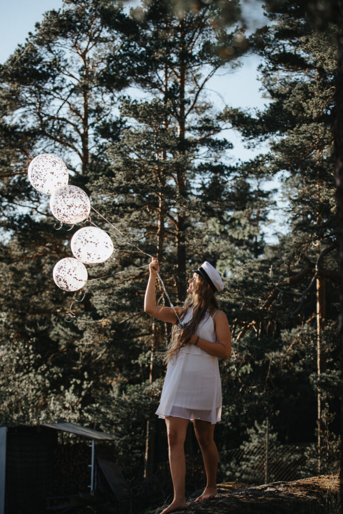 Student med ballonger i tallskog